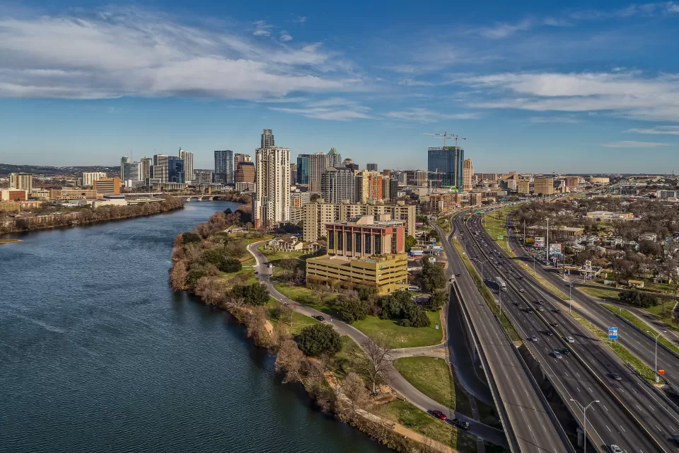 Austin skyline at dusk with a river on the left and I-35 running along the right.